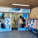 Photo of a Sue Ryder Charity Shop, with vinyl records stacked and large shirts displayed outside, under cover.